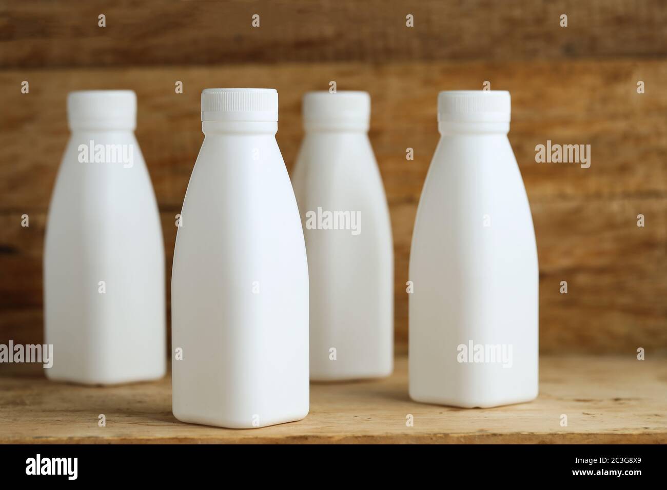 https://c8.alamy.com/comp/2C3G8X9/white-plastic-milk-bottles-on-retro-wooden-table-background-2C3G8X9.jpg