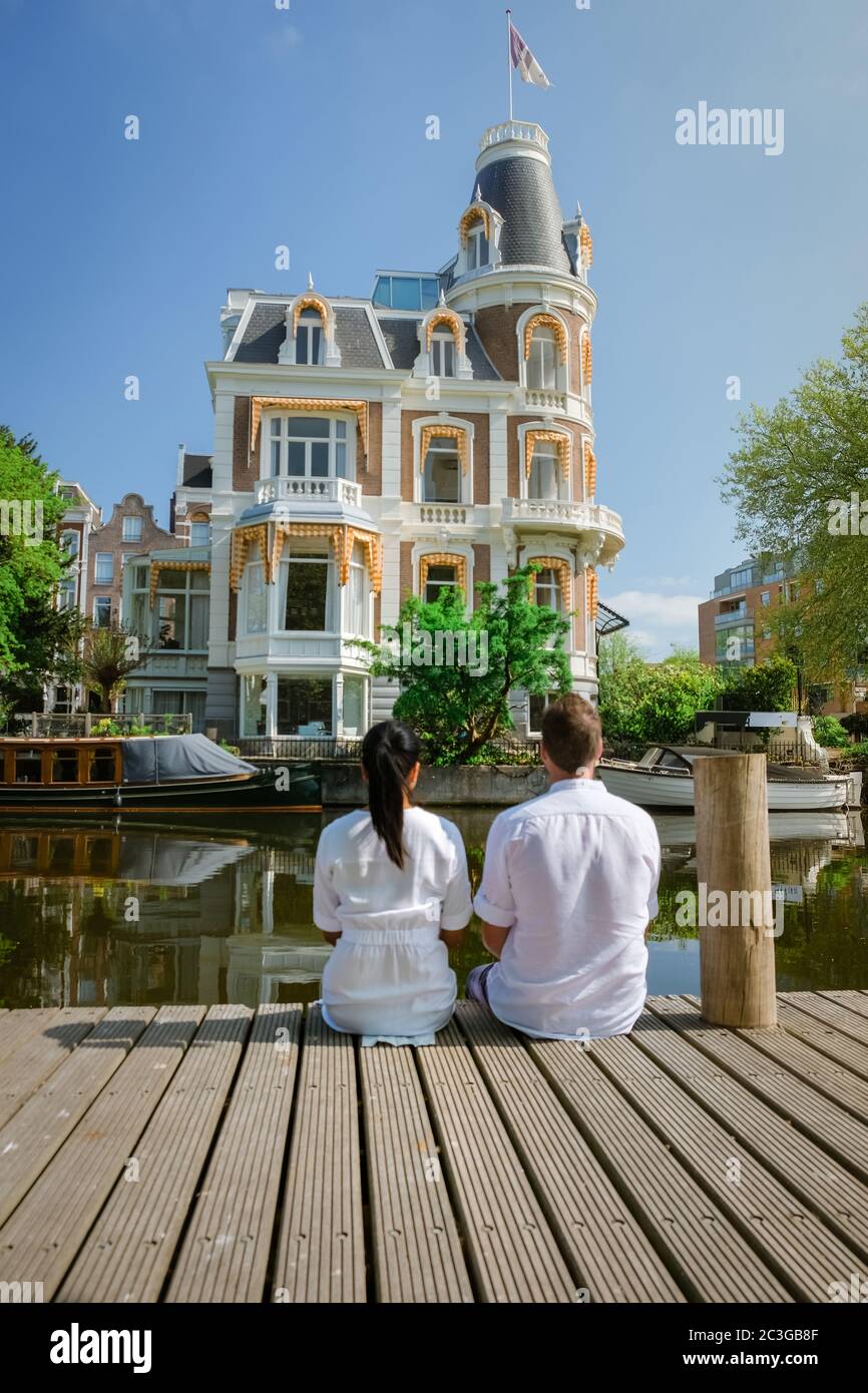 couple on a city trip to Amsterdam, men and woman relaxing by the canals of Amsterdam during Spring 2020 April in Europe Netherl Stock Photo