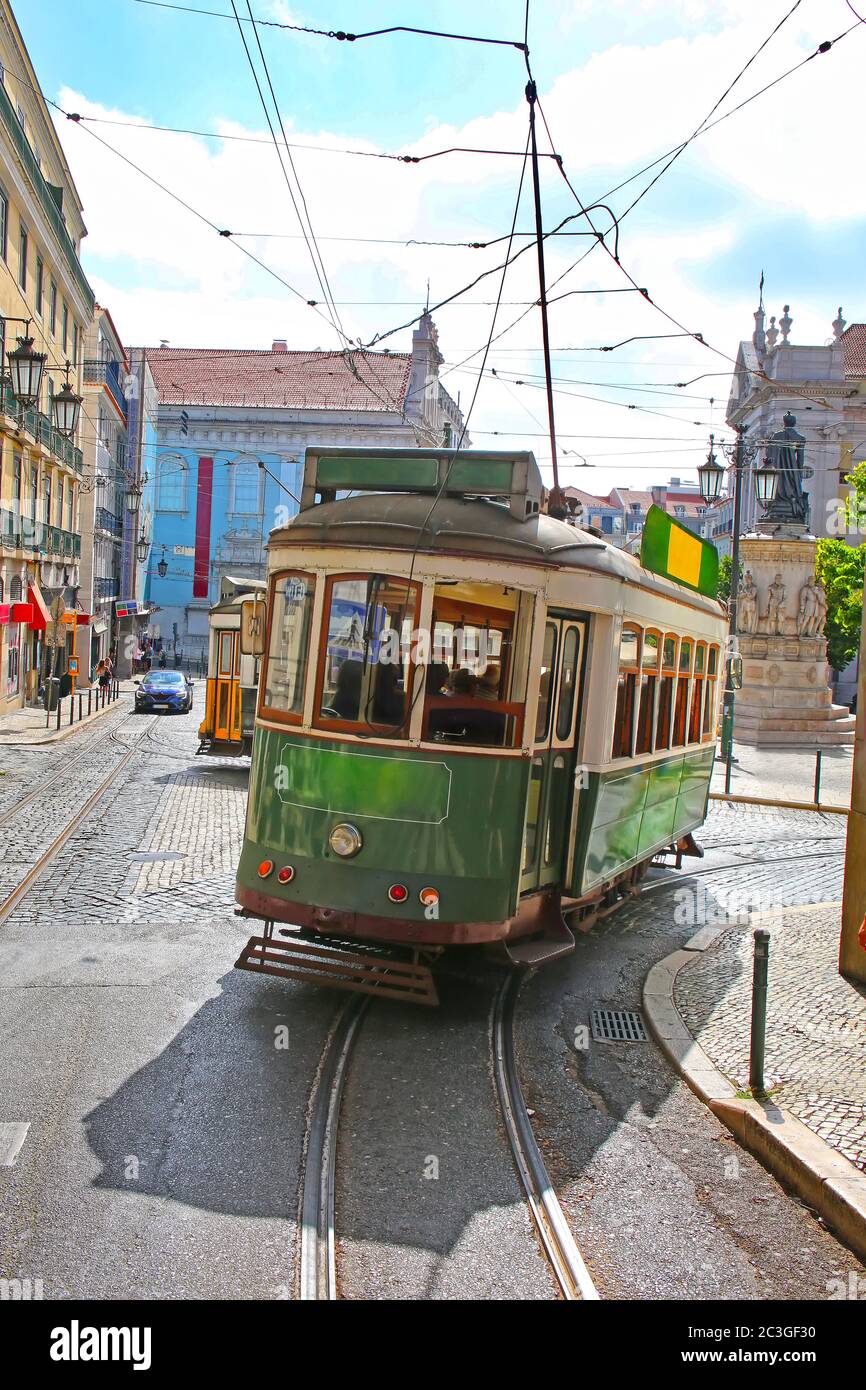 Historic green tram against old town streets, part of the tramway network since 1873, Lisbon, capital city of Portugal. Stock Photo