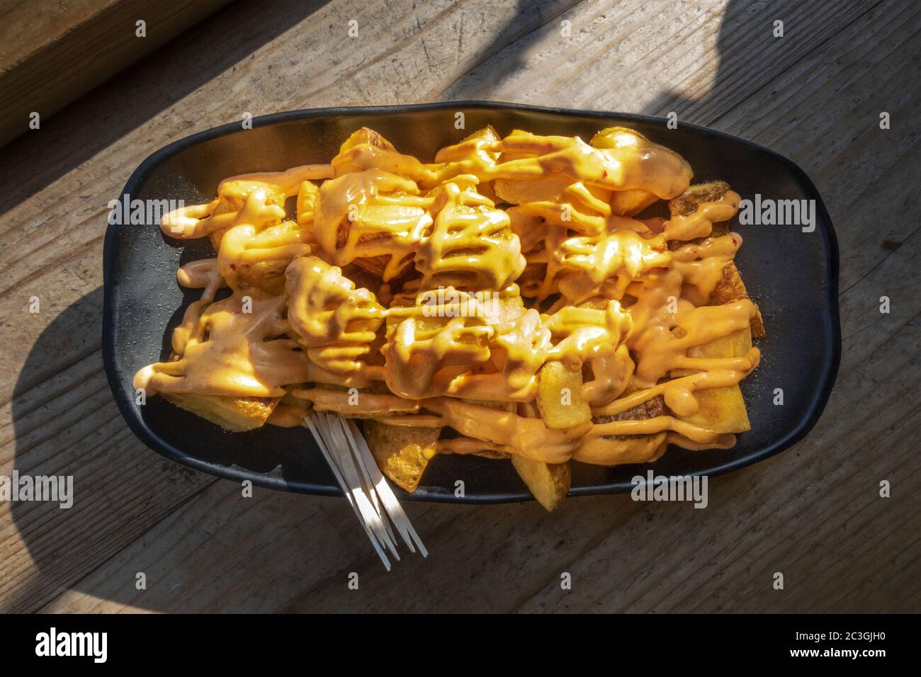 Patatas bravas, typical Spanish food. Potatos with a spicy sauce, overhead shot on a wooden table Stock Photo