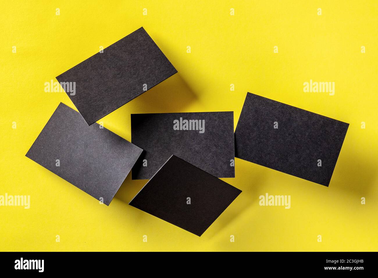 Thick black business cards, floating on a yellow paper background, a