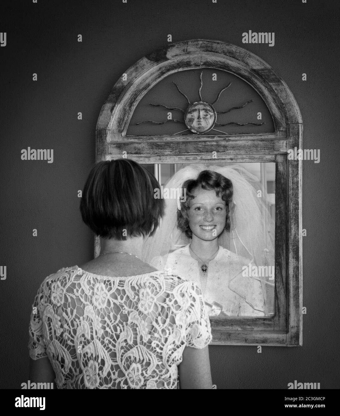 Older woman looking in mirror at younger reflection as a bride Stock Photo