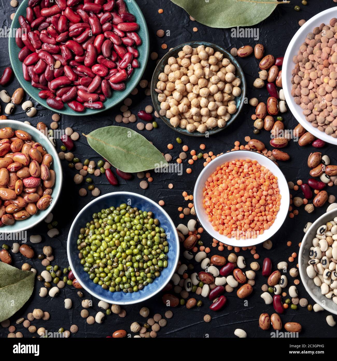 Legumes assortment, overhead square shot on a dark background. Lentils