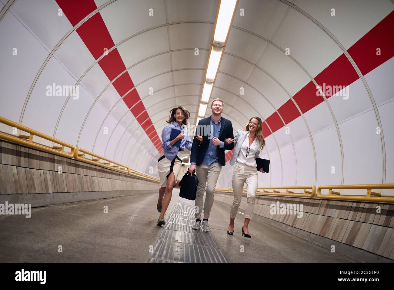 Successful young business people walking to platform at metro station. Stock Photo