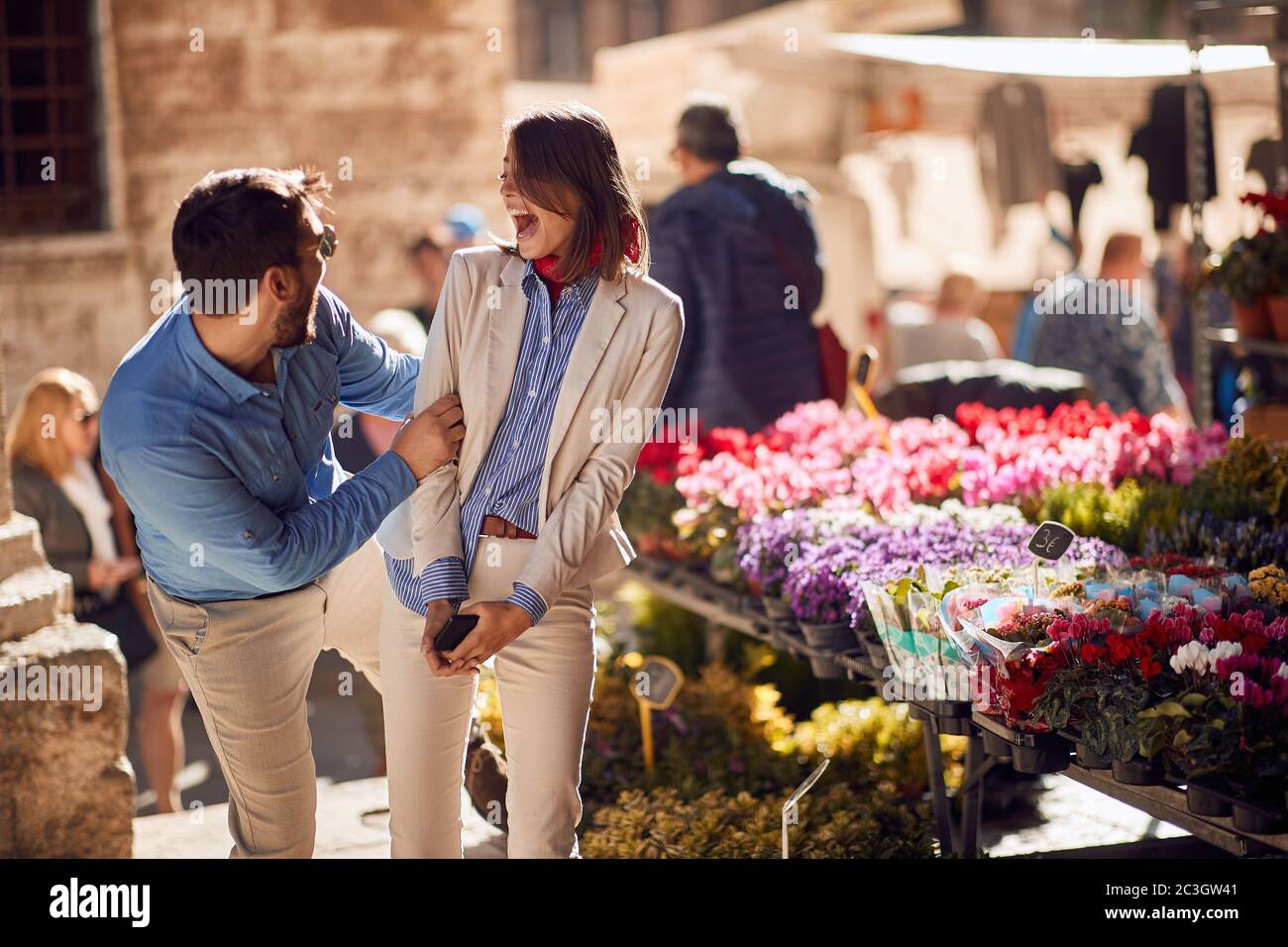 beautiful young female surprised by a male friend in front of flower shop in Italy, Toscana Stock Photo