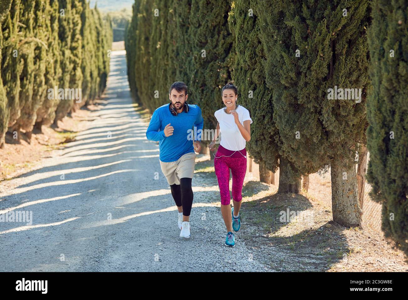 young caucasian female jogging uphill with personal trainer on a gravel
