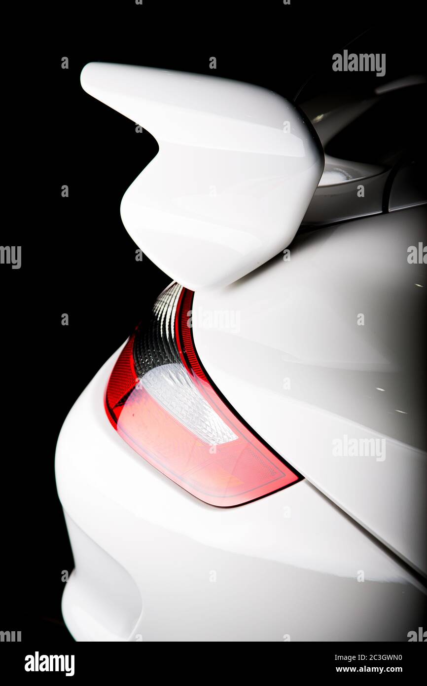 Vertical shot of a spoiler on a white luxury car under the lights isolated on a black background Stock Photo