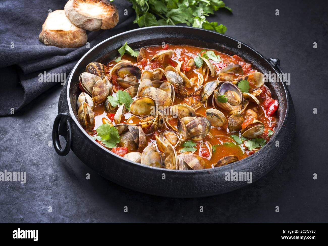 Cooked Japanese carpet shell with paprika and baguette in spicy tomato