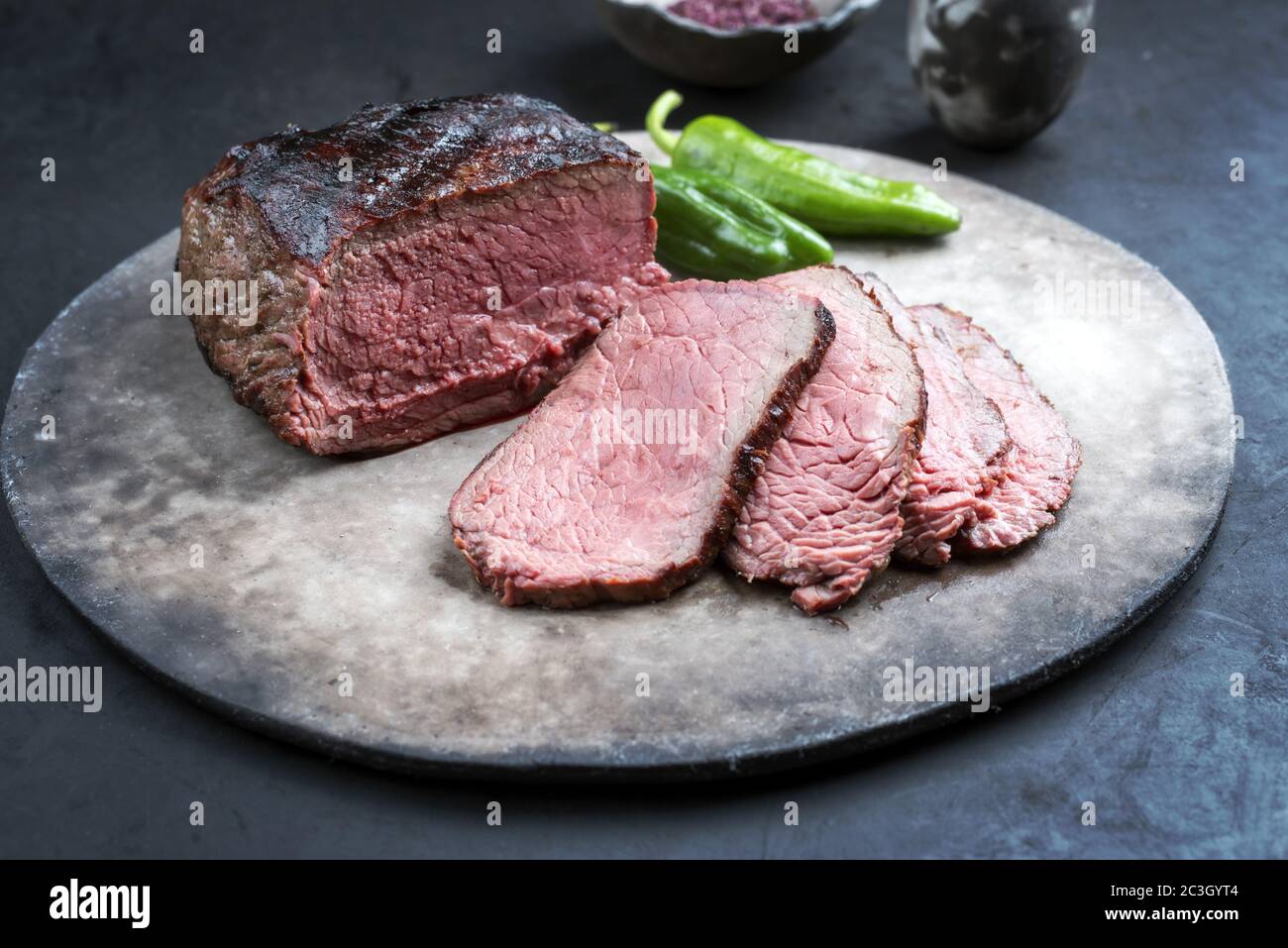 Traditional Commonwealth Sunday roast with sliced cold cuts roast beef with chili and red salt as closeup on a modern design pla Stock Photo