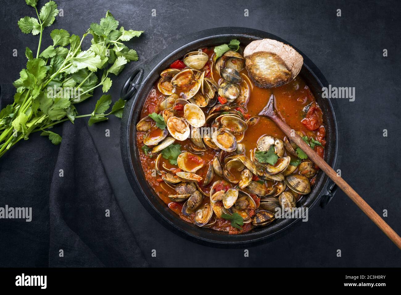Cooked Japanese carpet shell with paprika and baguette in spicy tomato
