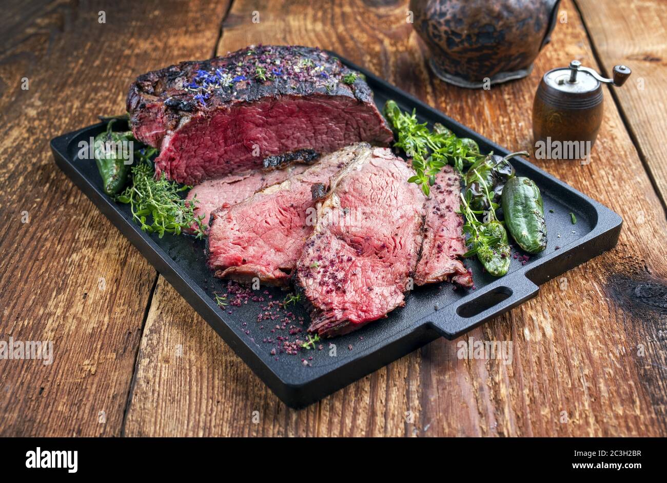 Traditional Commonwealth Sunday roast with sliced cold cuts roast beef with herbs and chili as closeup on a modern design tray Stock Photo