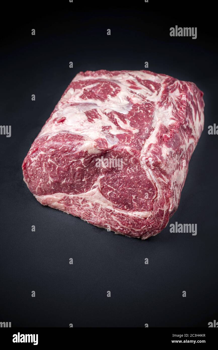 Raw dry aged wagyu entrecote beef steak roast as closeup on a black