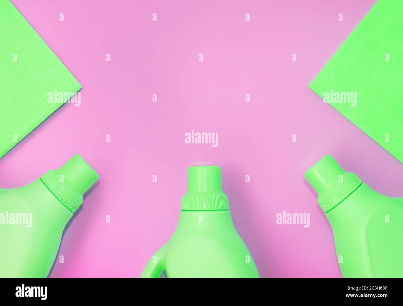 Green plastic bottles with chemicals for cleaning, rags for cleaning. Pink background. Cleaning concept Stock Photo