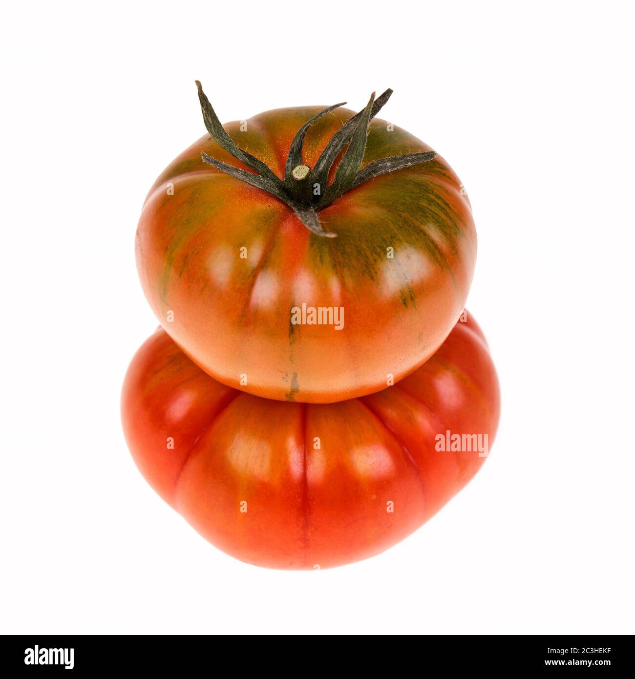Two heirloom Marmande tomatoes in a stack and isolated on white. Marmande are a continental ribbed variety of beefsteak tomato. Stock Photo