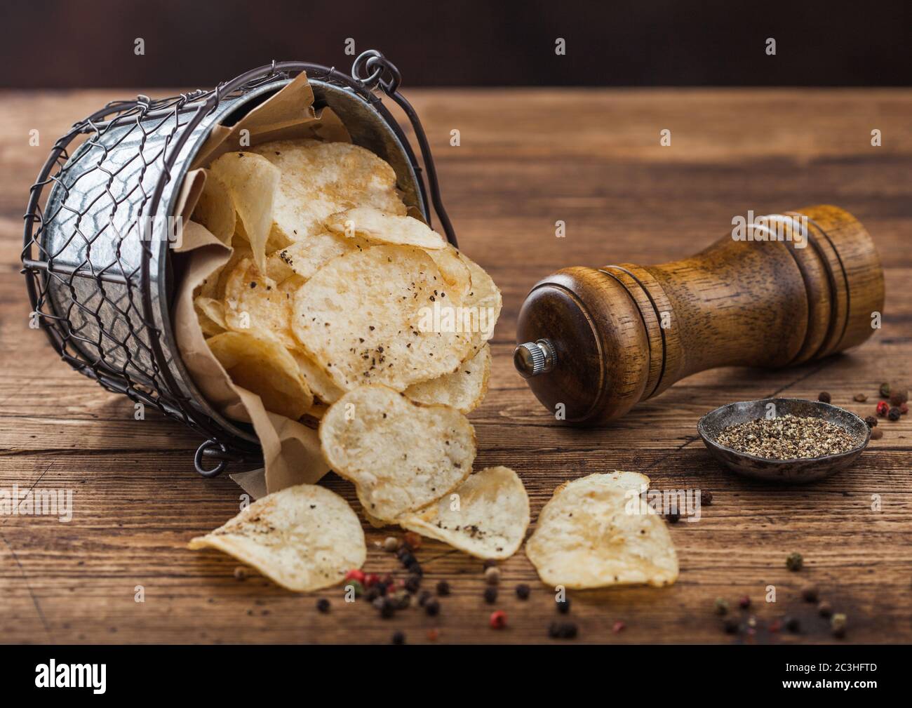 Potato crisps chips snack with black pepper snack bucket on dark wooden  background with mill and ground pepper Stock Photo - Alamy