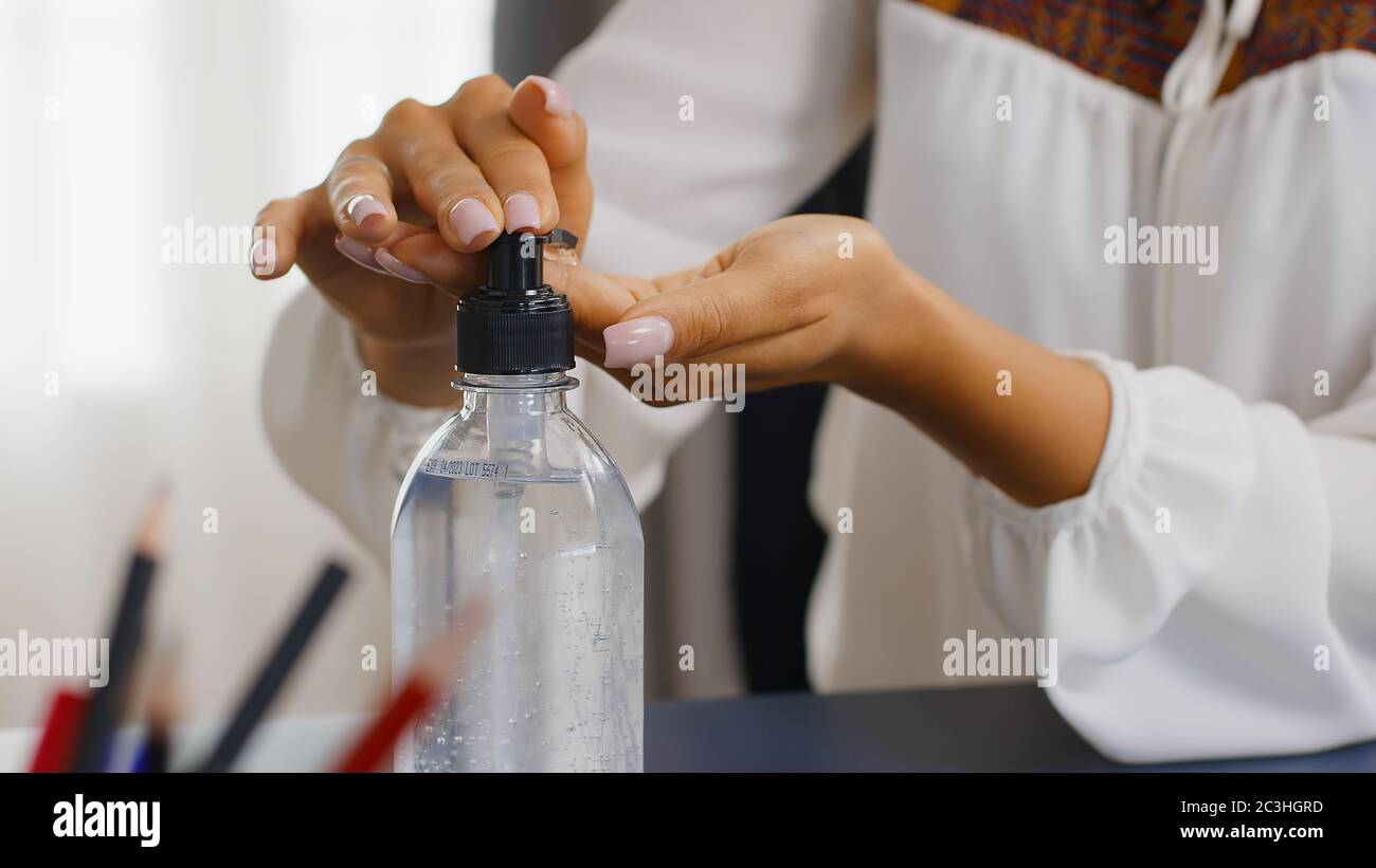 Close up of woman using hand sanitizer while working from home office ...