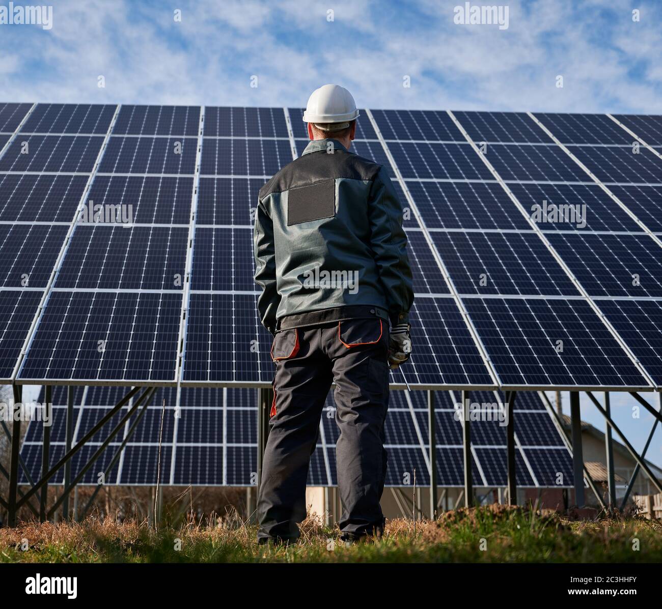 Back view of man electrician in work uniform and safety helmet looking