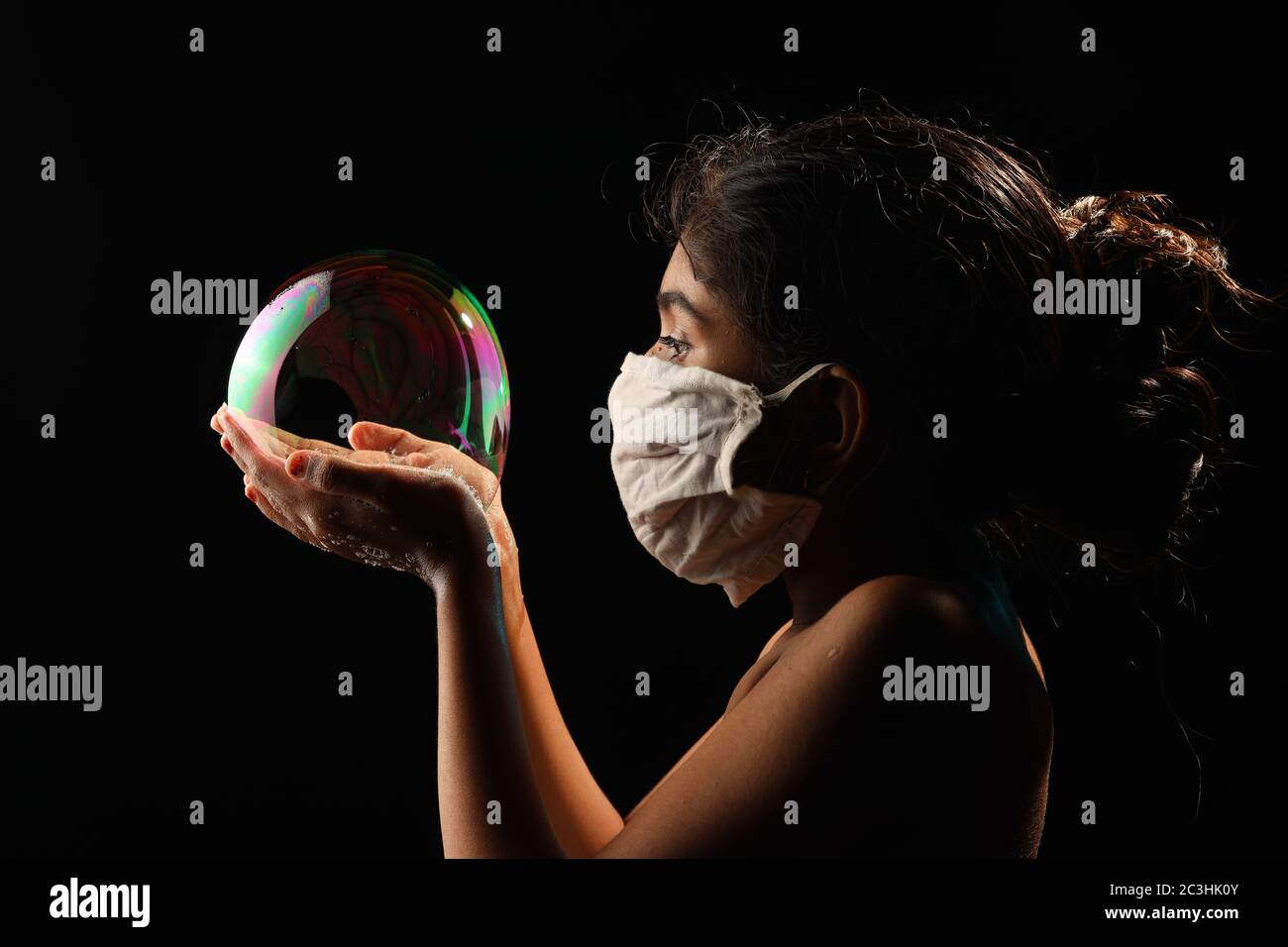 Midshot of a girl catching soap bubble  by wearing mask resemble a kid hopping for COVID free new world. Stock Photo