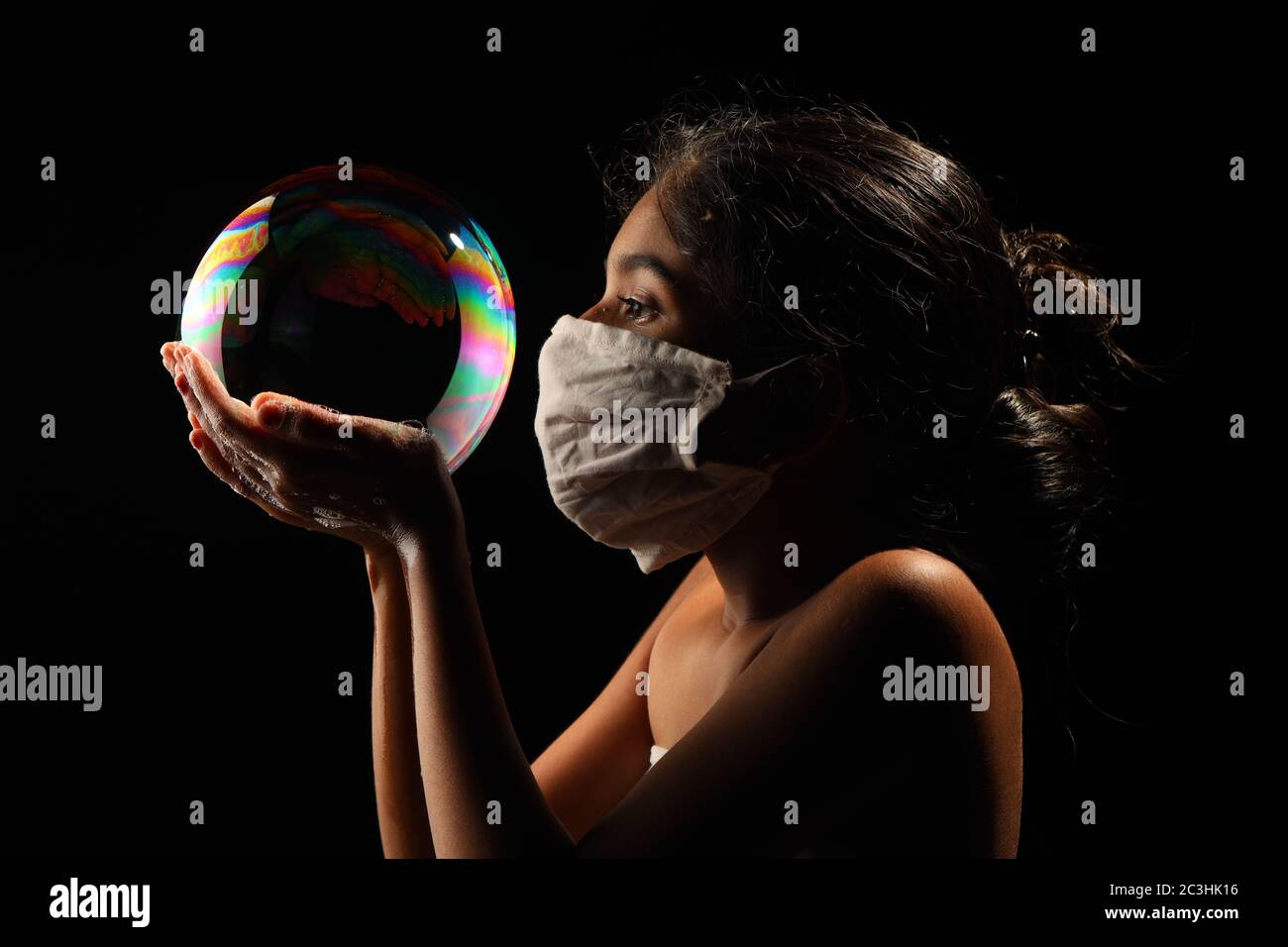 Midshot of a girl catching soap bubble  by wearing mask resemble a kid hopping for COVID free new world. Stock Photo