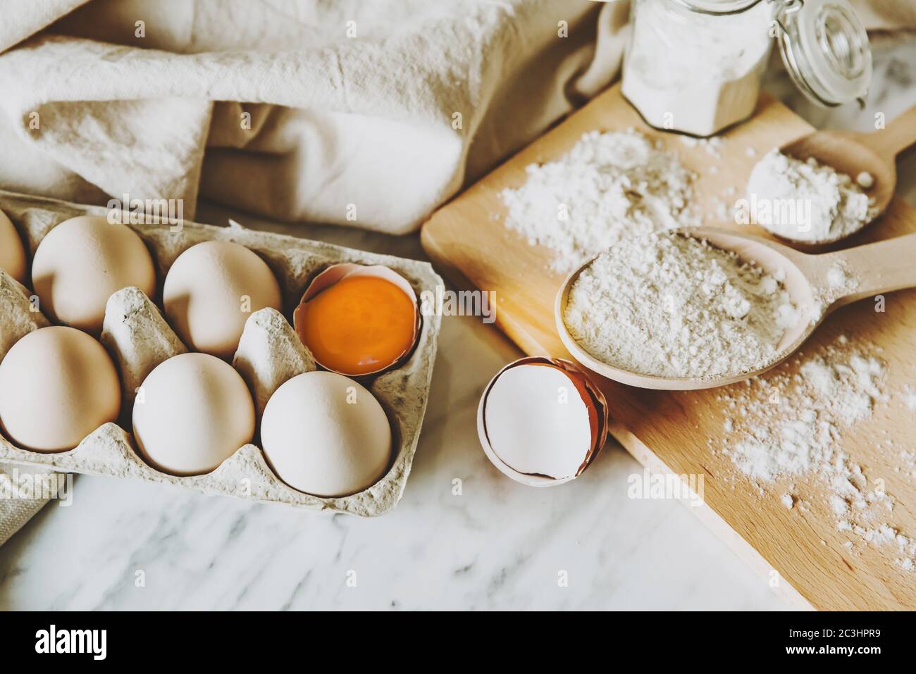 Baking utensils and baking ingredients with eggs, wheat flour, egg yolks for pastry. Cake, pasta or dough recipe ingredients. Top view on table Stock Photo