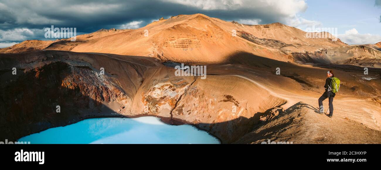 Beautiful panoramic view of idyllic geothermal mountain scenery at Askja volcano with female hiker looking towards Viti volcanic lake in the central h Stock Photo