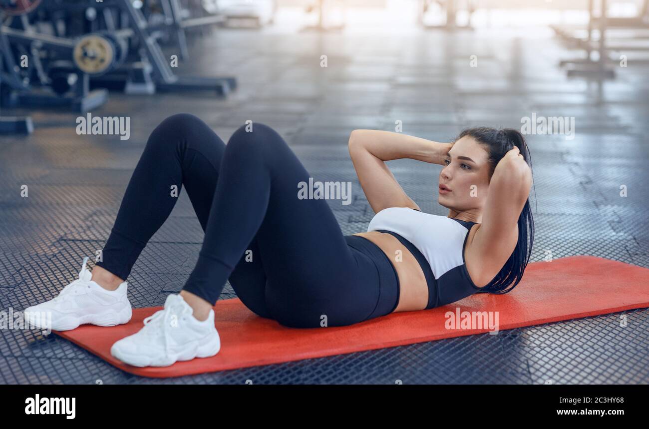 Strong young woman doing abs exercises on floor at fitness centre Stock Photo