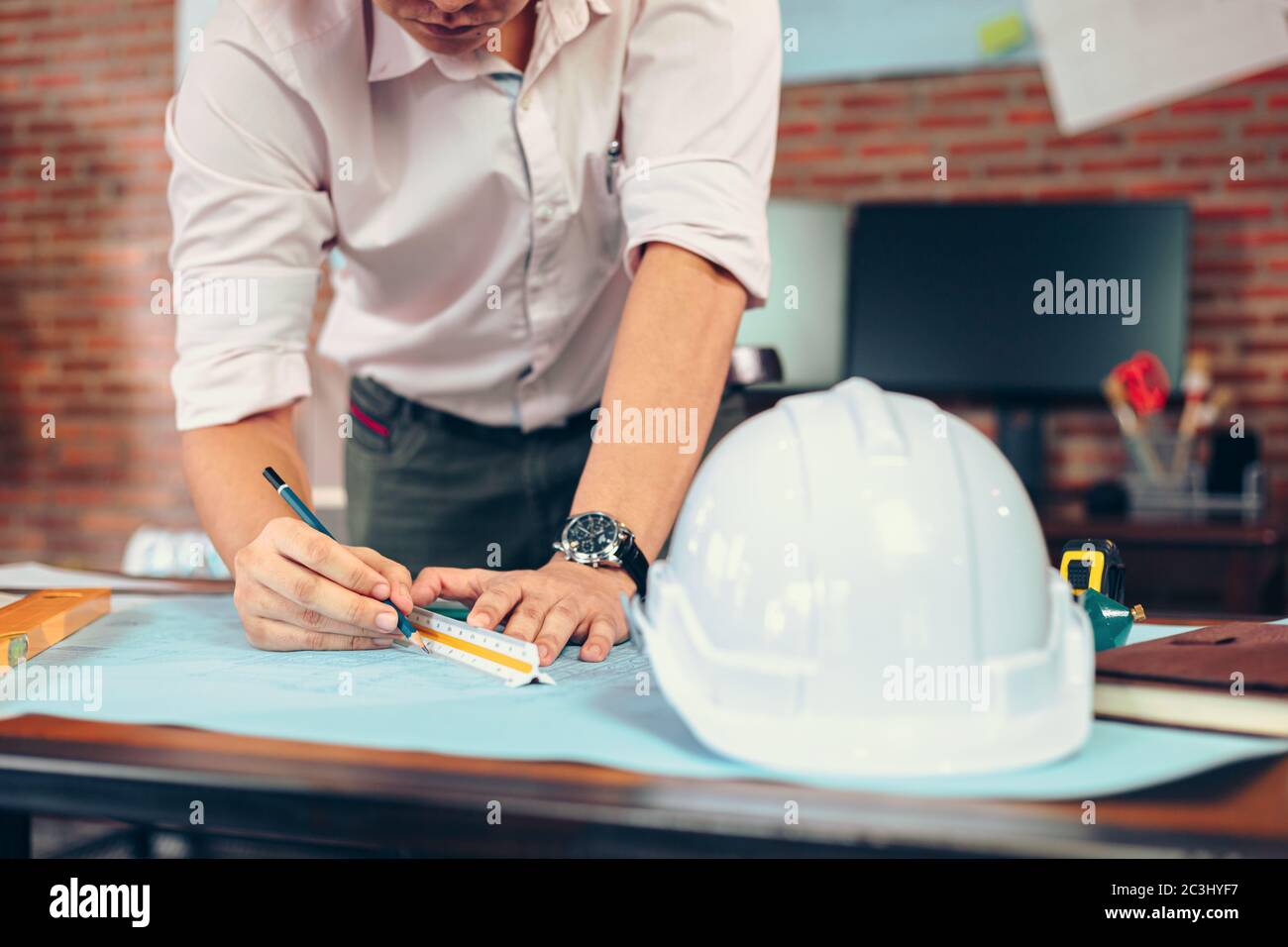 engineers holding a pen pointing to a building and  drawing outlay construction plan as guide for builders with details Stock Photo