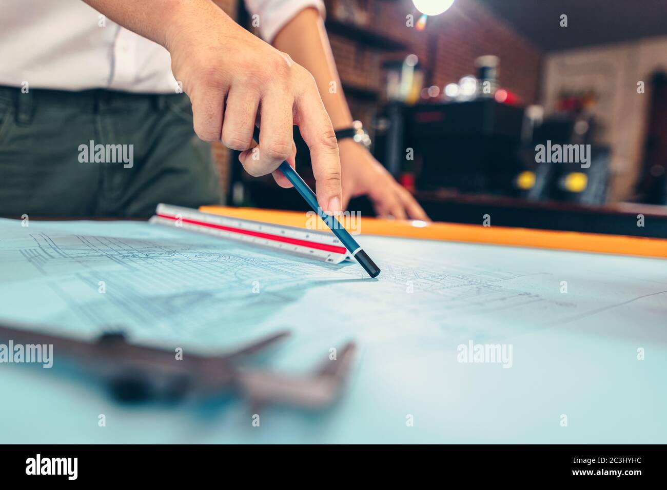 engineers holding a pen pointing to a building and drawing outlay