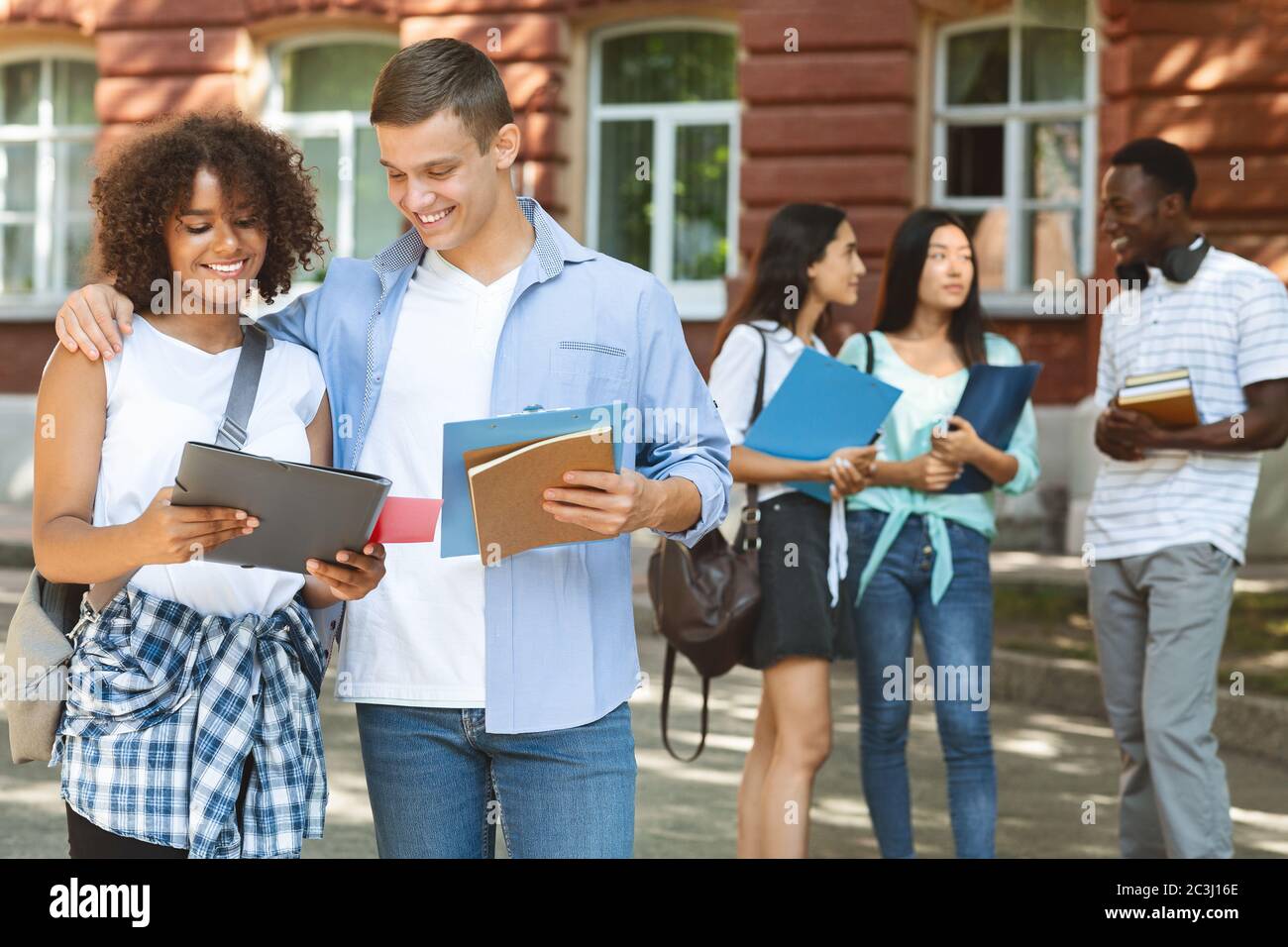 Cheerful student embracing his female classmate outdoors, greeting with exam pass Stock Photo