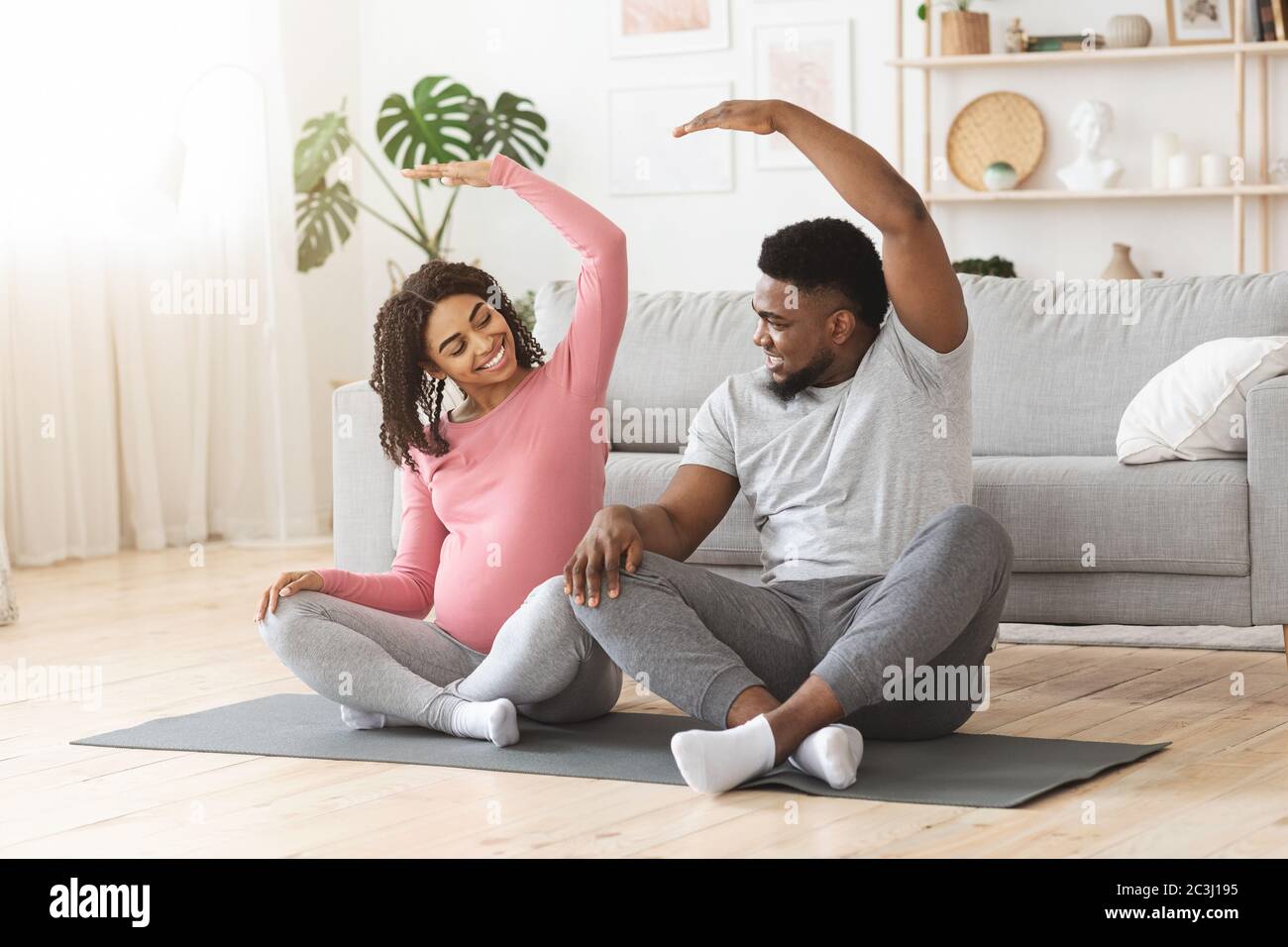 Active african expecting couple exercising together at home Stock Photo