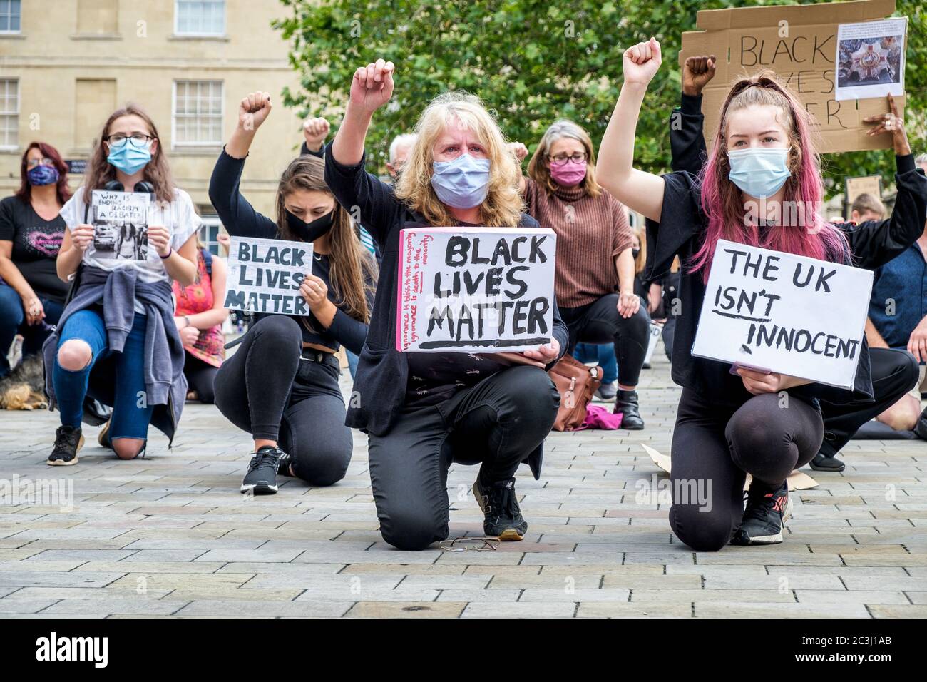 Chippenham, Wiltshire, UK. 20th June, 2020. BLM Protesters hold up BLM placards and signs as they take a knee during a Black Lives Matter BLM protest rally in the town's Market Place. The rally was organised in order for local people to draw attention to racism in the UK and to show solidarity with other BLM protests that have been taking place around the world after the death of George Floyd who died in police custody on 25th May in Minneapolis. Credit: Lynchpics/Alamy Live News Stock Photo