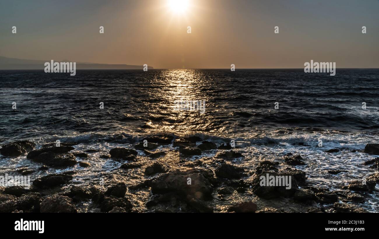 Backlit seascape, with the sun's rays painting, on the sea, a luminous ...
