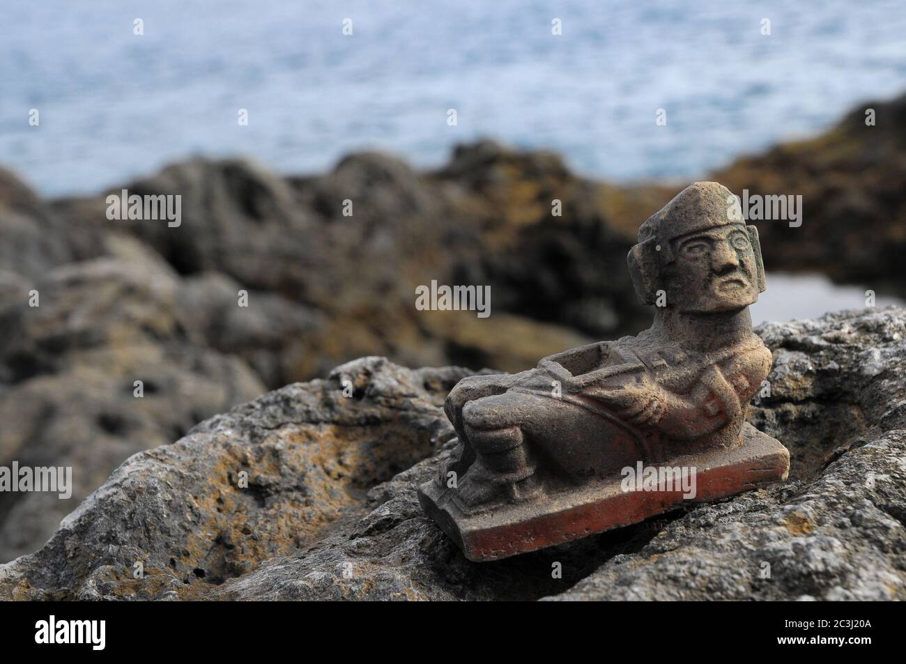 Ancient Maya Statue on the Rocks near Ocean Stock Photo