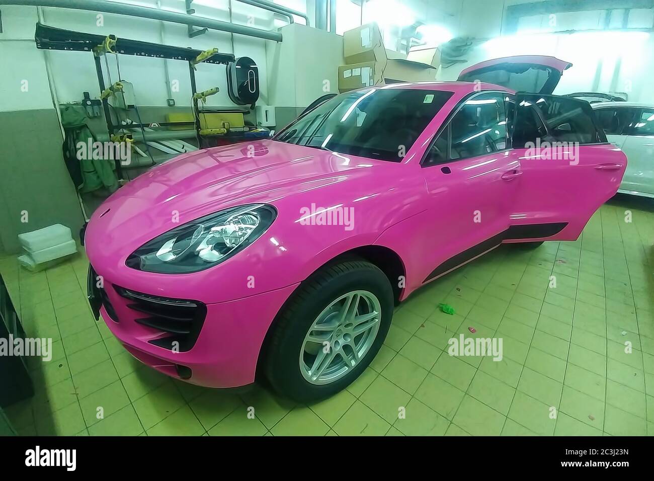 Moscow, Russia - May 09, 2019: Porsche Macan in service center, car wrapping, putting pink vinyl foil or film on car. Stock Photo