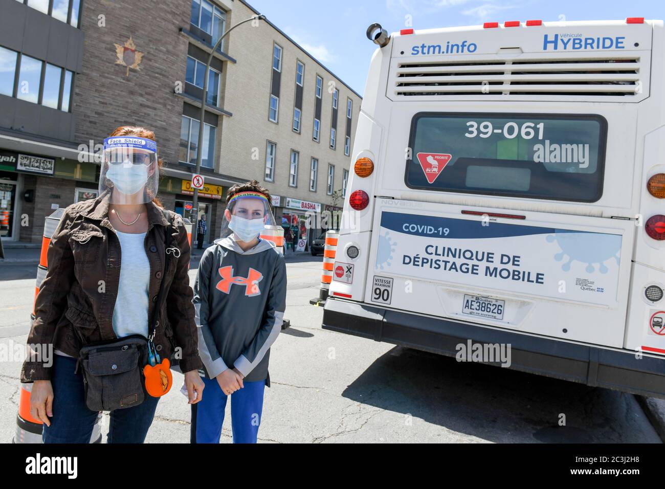 Mother & son wearing protective face masks and face shields during Covid-19 Pandemic standing in front of Covid19 mobile free testing clinic, Montreal Stock Photo