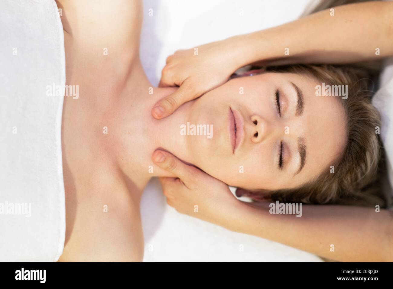 Young blond woman receiving a head massage in a spa center. Stock Photo