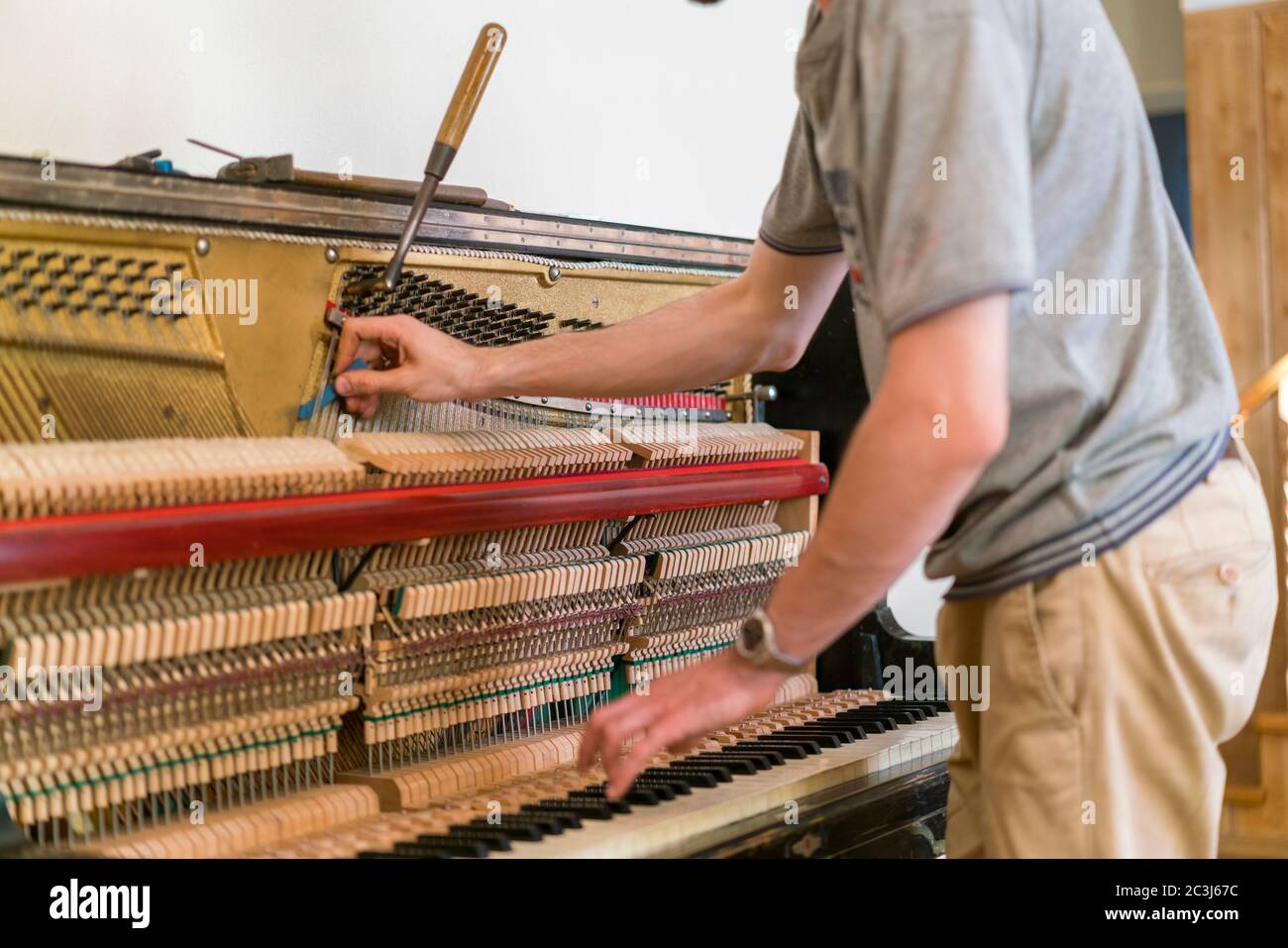 Piano tuning process. closeup of hand and tools of tuner working on grand  piano. Detailed view of Upright Piano during a tuning Stock Photo - Alamy