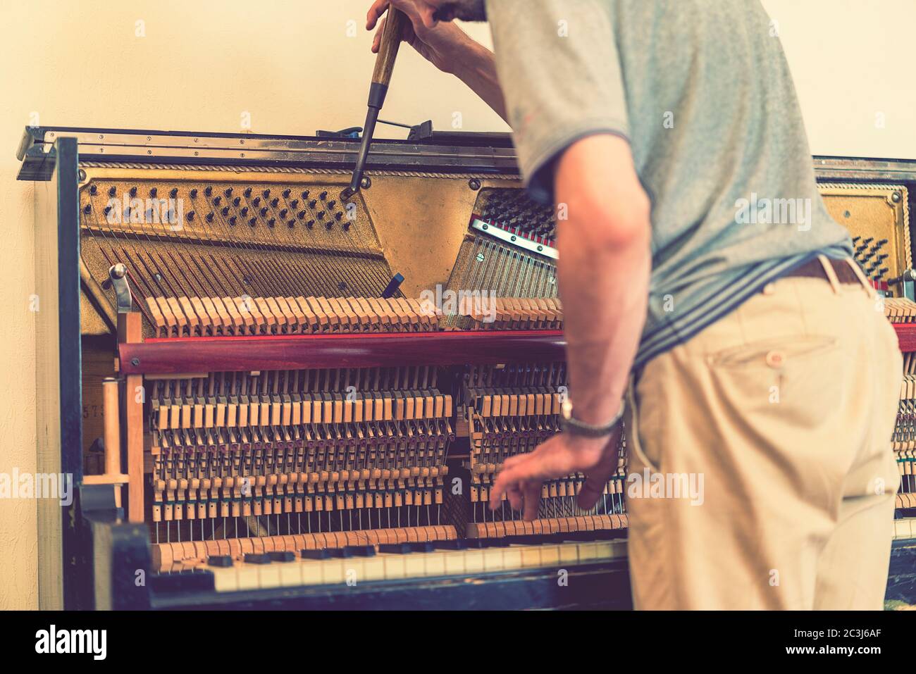 Piano tuning process. closeup of hand and tools of tuner working on