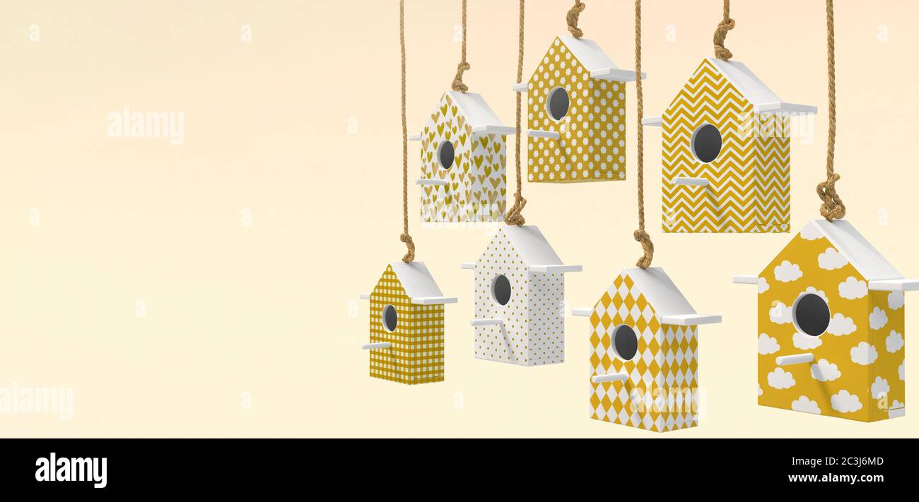 A set of painted birdhouses are suspended on a rope. Birdhouses with yellow and white patterns isolated on a light yellow background with space for te Stock Photo