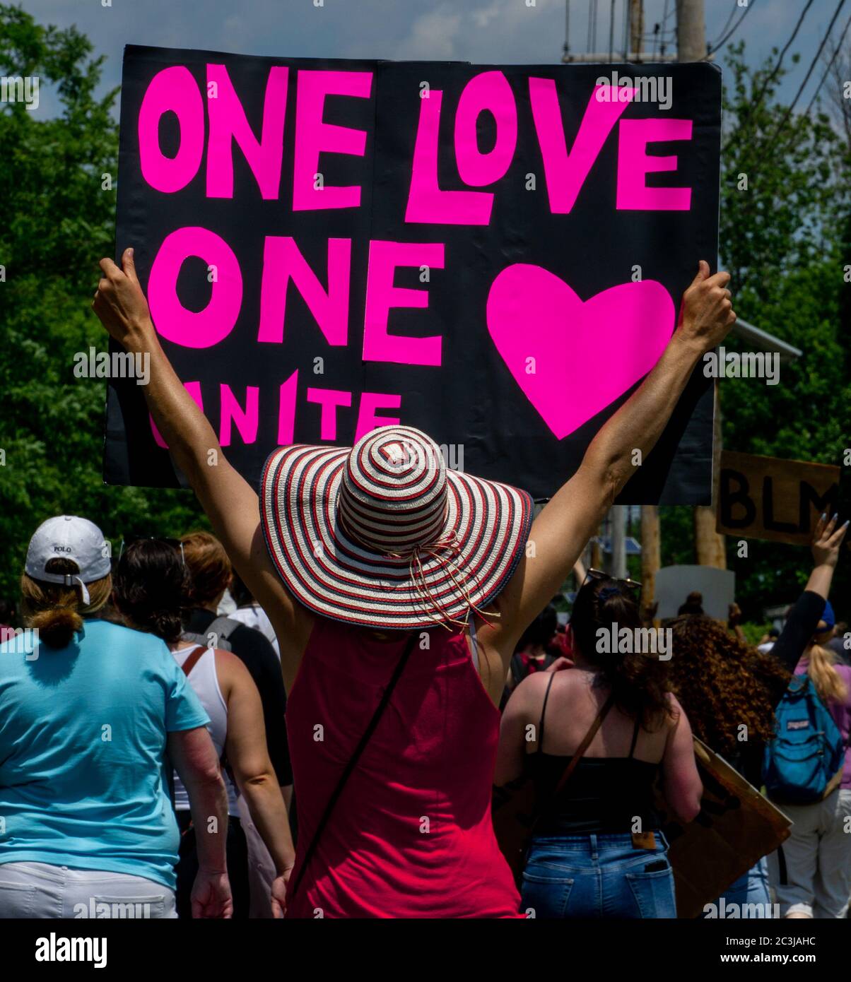 Juneteenth March Black Lives Matter Protest George Floyd - Woman holding ONE LOVE UNITE sign wearing nice hat walking in street photograph in Teaneck, Stock Photo
