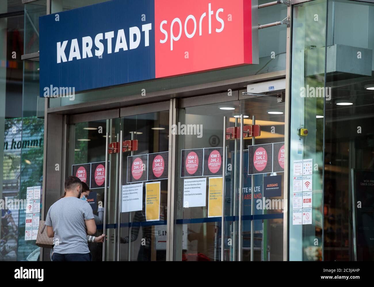Dortmund, Germany. 20th June, 2020. Two passers-by are standing at an entrance to a Karstadt Sports branch. In addition to the planned closure of dozens of branches of the department store chain Galeria Karstadt Kaufhof, 20 of the 30 branches of the Karstadt Sports subsidiary are also to close. Credit: Bernd Thissen/dpa/Alamy Live News Stock Photo