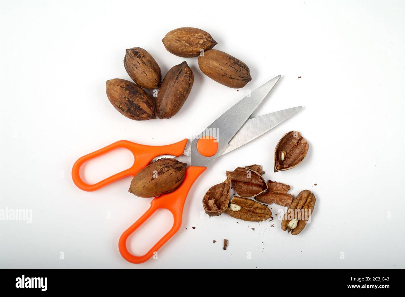 Some pecan nuts and kitchen scissors with nutcracker isolated on white background Stock Photo