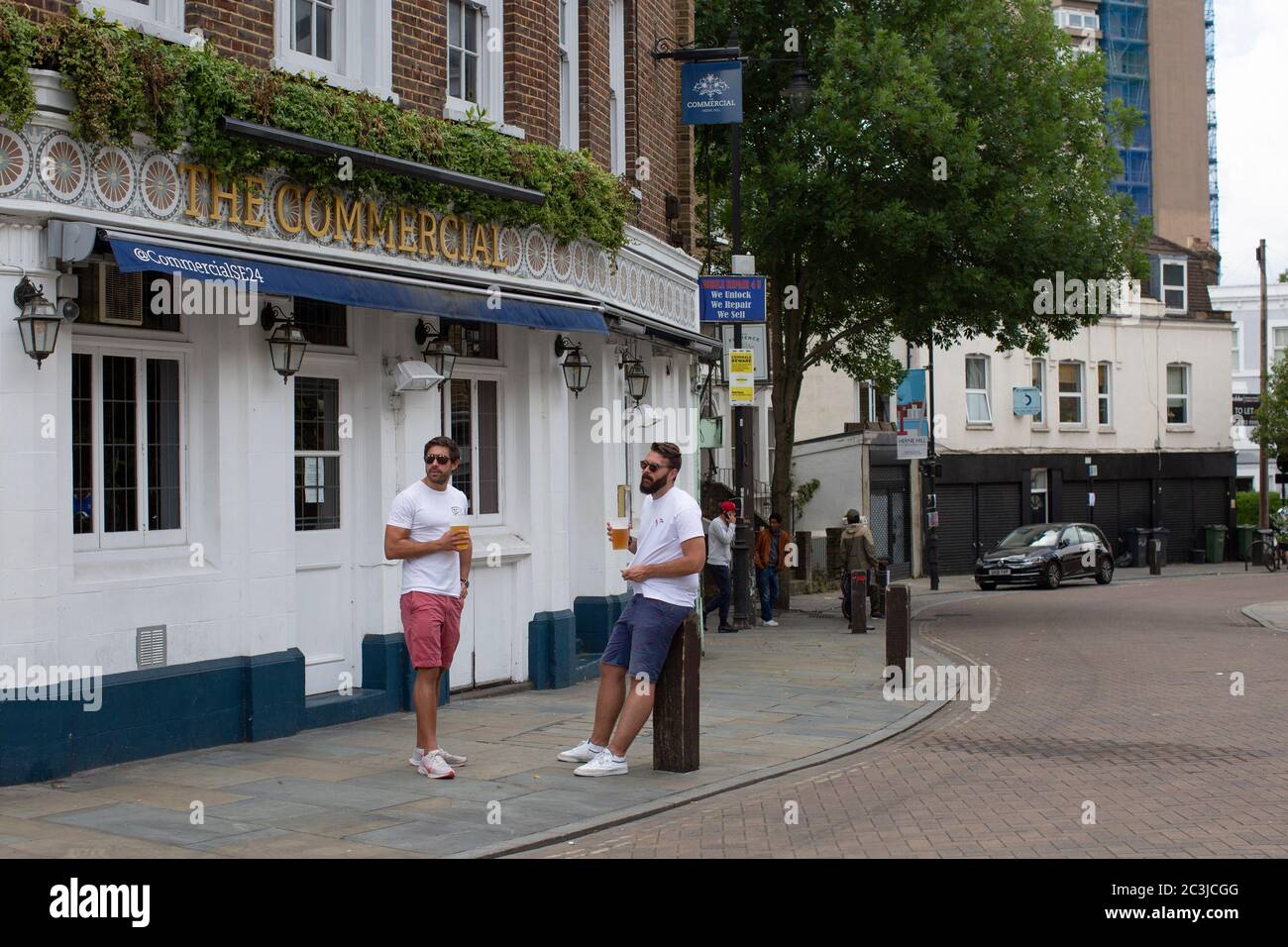Herne Hill, London, England. 20th June 2020. Two men standing outside a pub drinking beer as non-essential businesses reopen on Railton Road next to Herne Hill Station in South London following the British government relaxing coronavirus lockdown laws significantly from Monday June 15. (photo by Sam Mellish / Alamy Live News Stock Photo