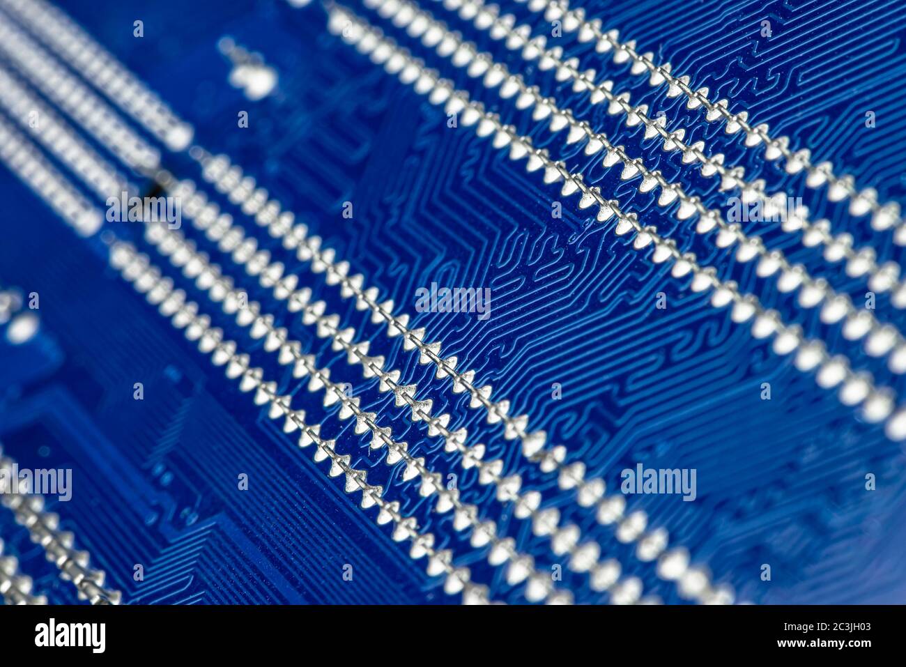 Macro photo of electrical paths on blue circuit board, visible soldering of the semiconductor tip. Stock Photo