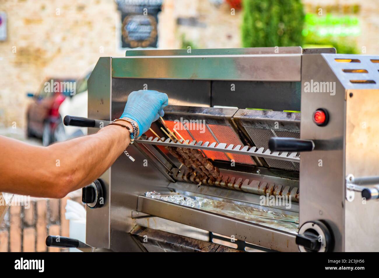 A man cooks the Arrosticini, skewers of sheep meat, a typical dish of  Abruzzo cuisine, on a gas grill, in a stall of a village festival. Grilled  meat Stock Photo - Alamy