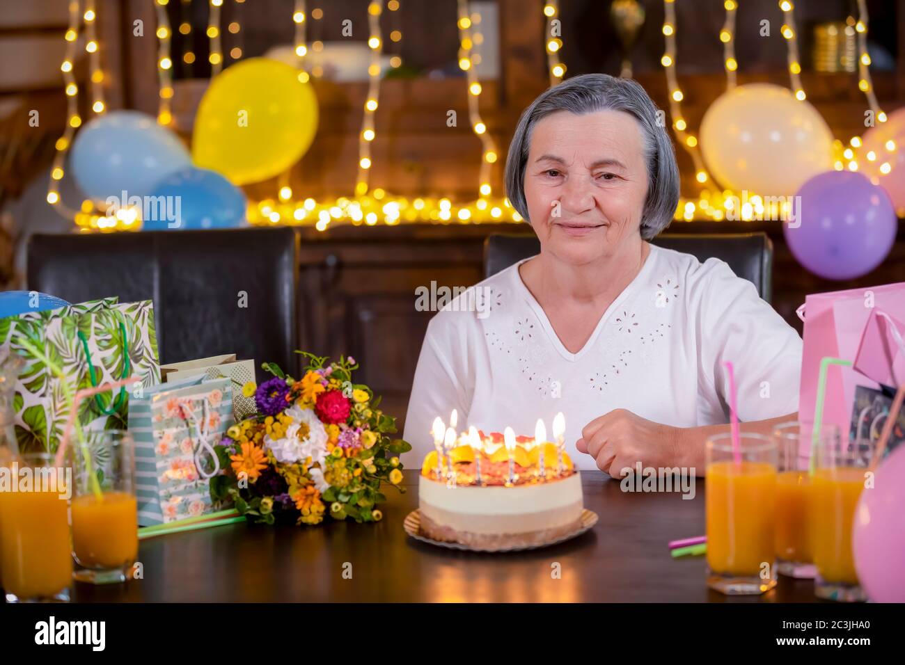 Senior woman with birthday cake at anniversary or Mothers Day party. Celebrating life and love concept. Mothers day concept. Stock Photo