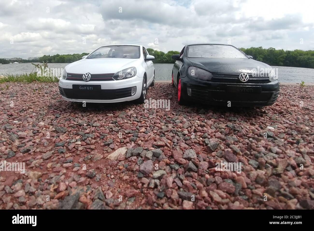 Moscow, Russia - May 03, 2019: Two toy cars in river park. 2 Volkswagen golf mk6 stand on a pebble beach. White and black GTI stand next to each other. Moscow river at background Stock Photo