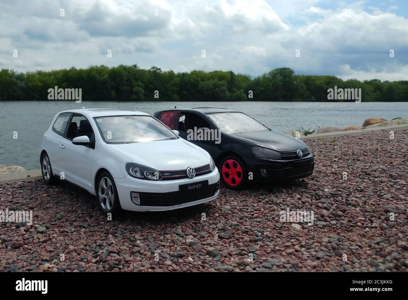 Moscow, Russia - May 03, 2019: Two toy cars in river park. 2 Volkswagen golf mk6 stand on a pebble beach. White and black GTI stand next to each other. Moscow river, Kolomenskoe Stock Photo