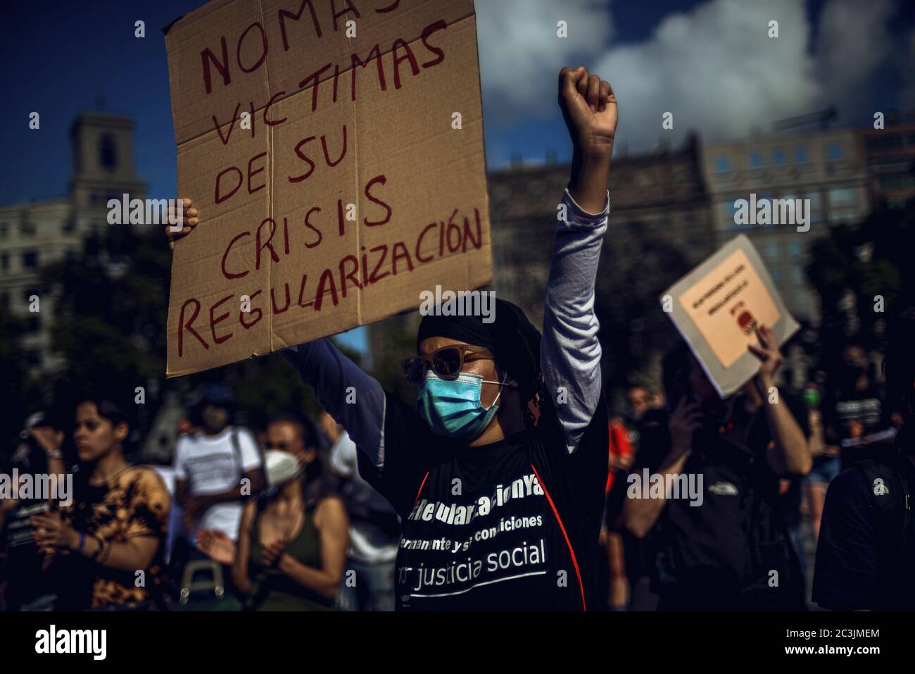 Barcelona, Spain. 20th June, 2020. An immigrant protests for documents and regulation holding a placard reading 'no more victims of your crisis - regulation' after the completion of a gradual way to 'the new normal' rolling back a nationwide strict lockdown due to the continuous spread of the corona virus. Illegal migrants without documents are among the most affected by the struggling economy due to the corona virus while they remain excluded from all state aid programs. Credit: Matthias Oesterle/Alamy Live News Stock Photo