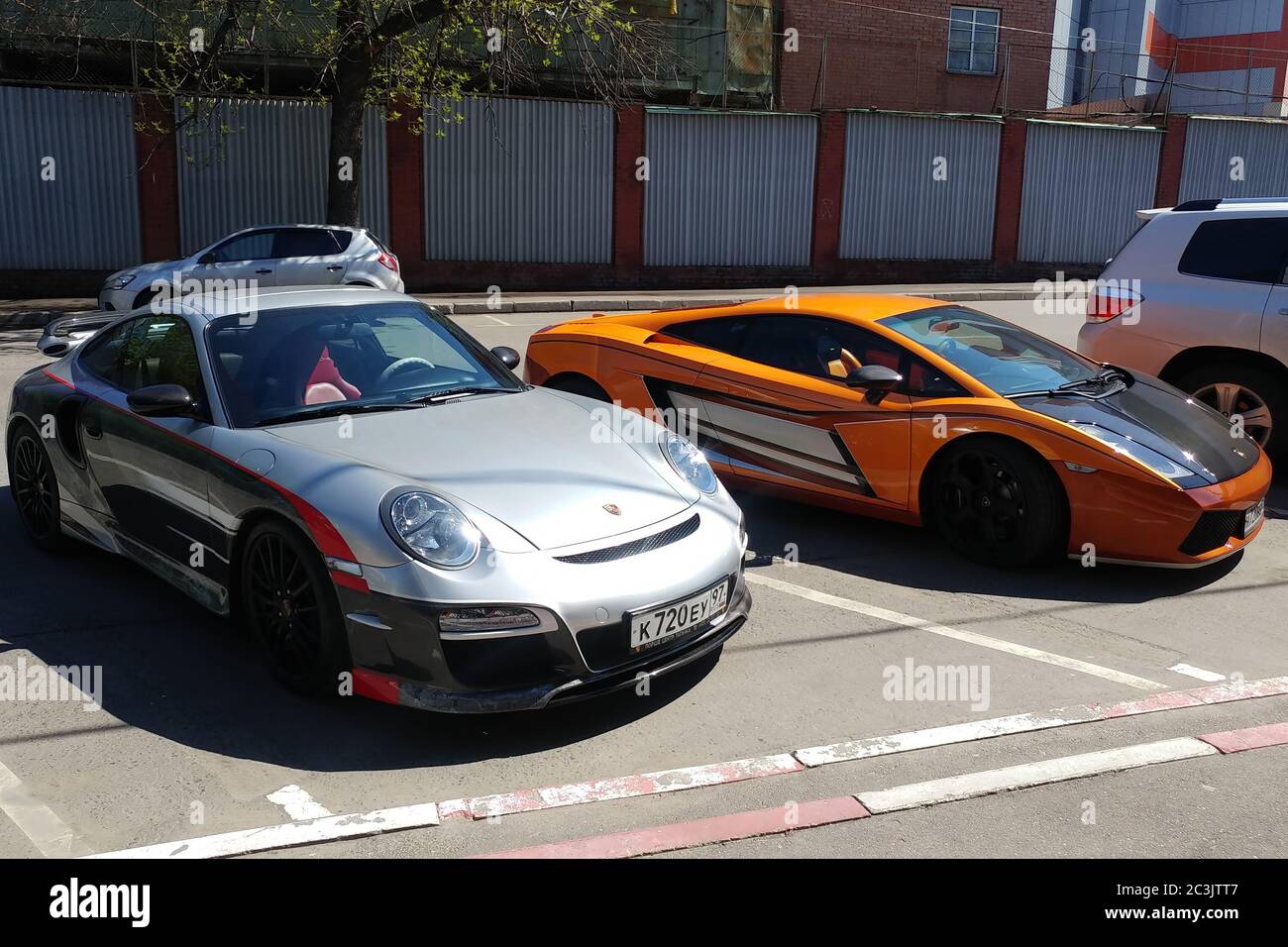 Moscow, Russia - April 14, 2019: exclusive Porsche 911 with aerography and Mansory tuning near bright orange Lamborghini Gallardo with carbon hood and other parts parked on the street Stock Photo